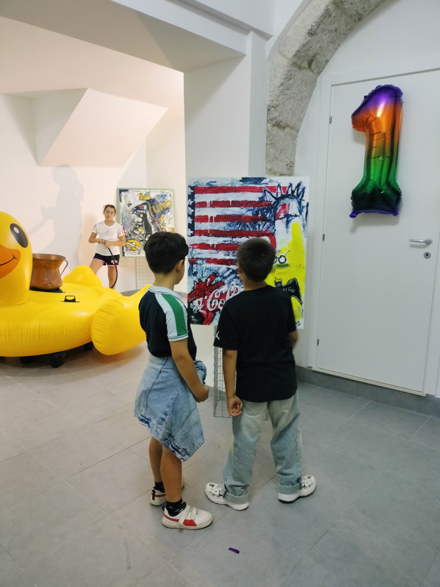 Due bambini osservano un quadro cercando di riconoscere i simboli dei loro supereroi preferiti.